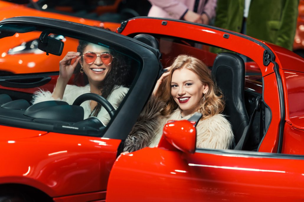 Jeunes femmes trendy au volant d'une voiture de luxe rouge